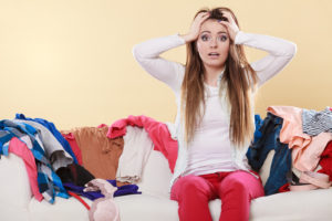 Disorganized woman surrounded by seasonal items clothing considers utilizing a storage unit