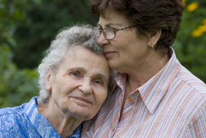 A worried daughter hugs her aging mother