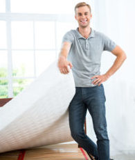 A young man moves his mattress into a storage unit
