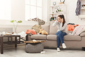 A young woman in a cluttered and messy room before turning to renting a storage unit