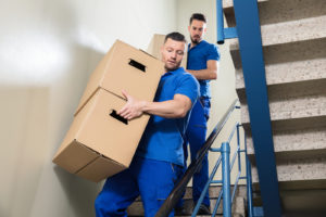 Hired movers help move items downstairs.